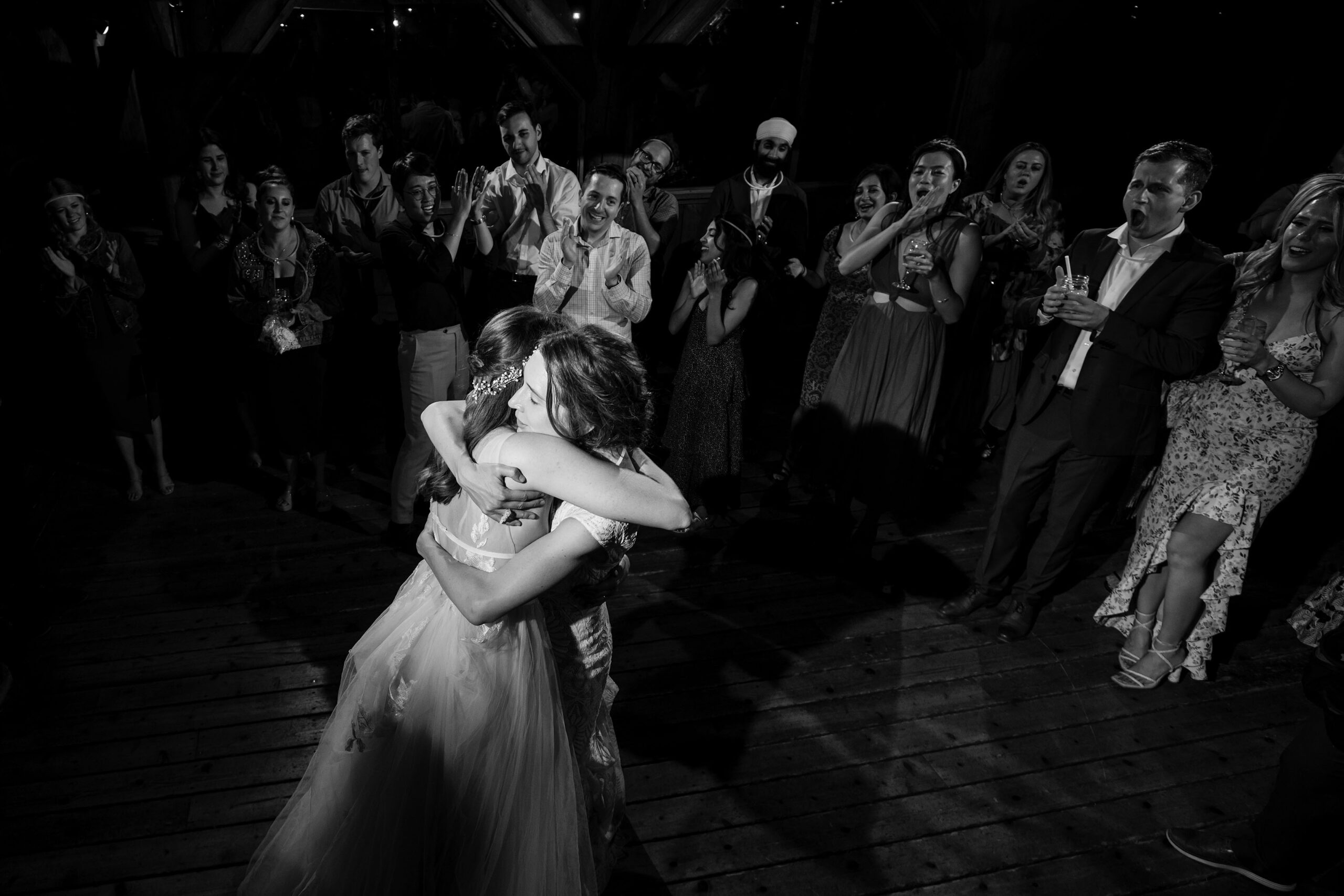 Guests clap as the two brides hug at the end of their rreception