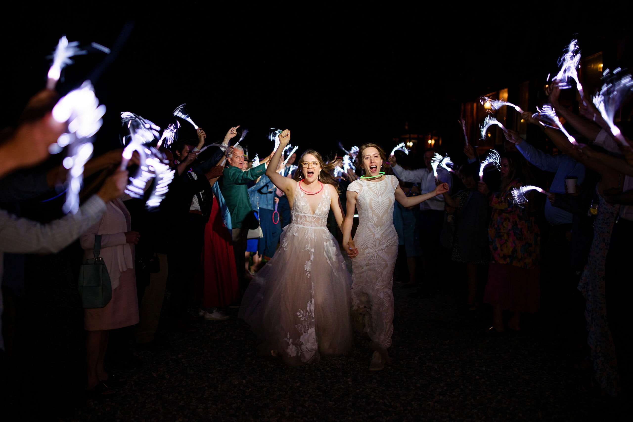 Miranda and Alice exit their wedding reception as guests wave fiber optic wands