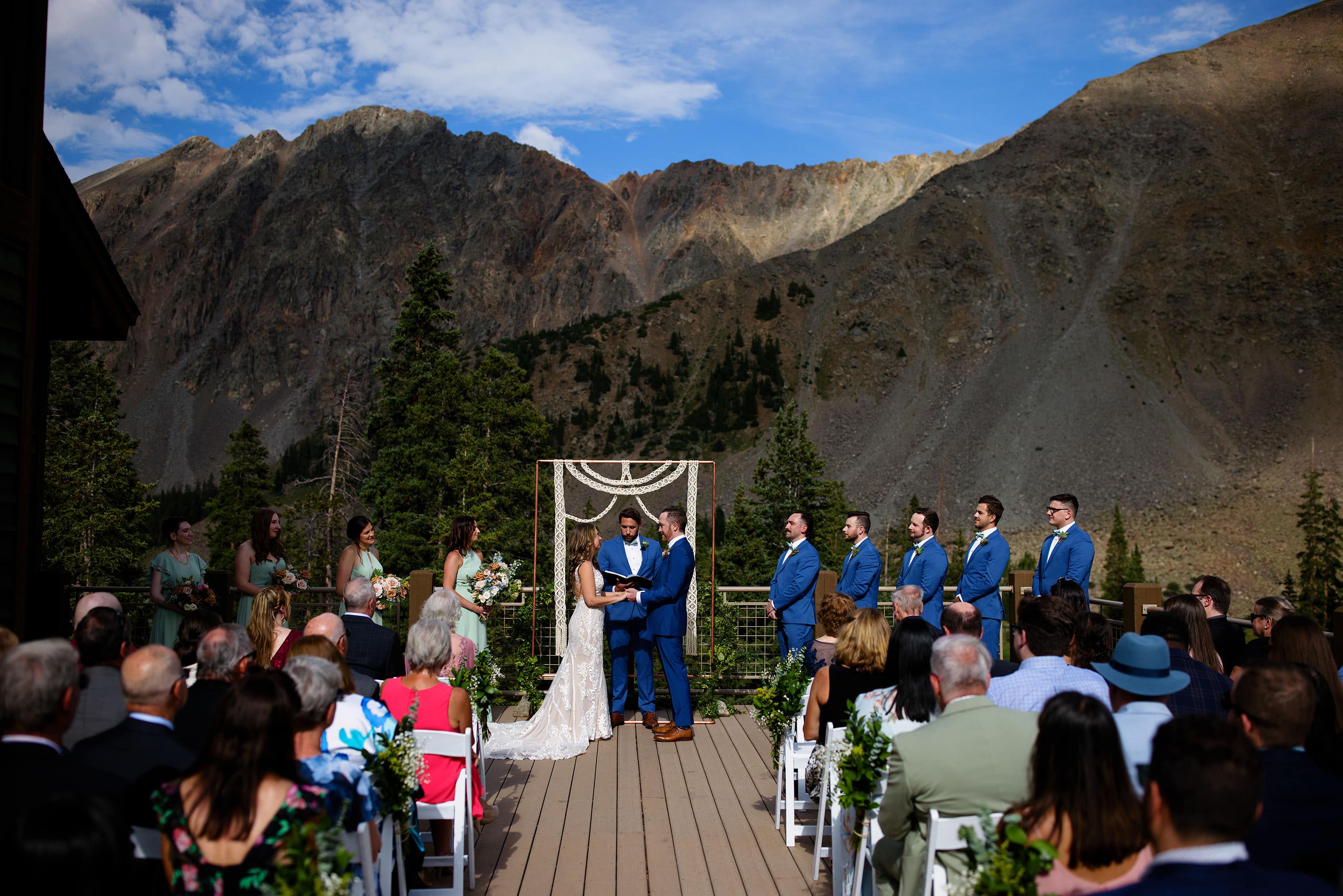 The bride and groom hold hands during their ceremony at Arapahoe Basin Black Mountain Lodge