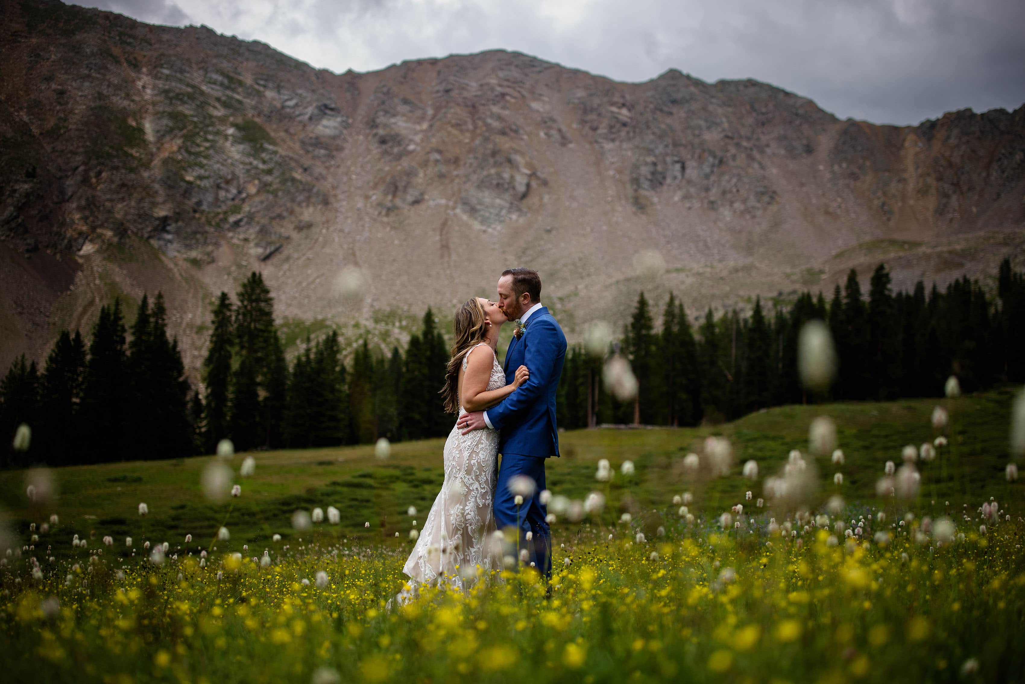 The newlyweds share a kiss in wildflowers at Arapahoe Basin