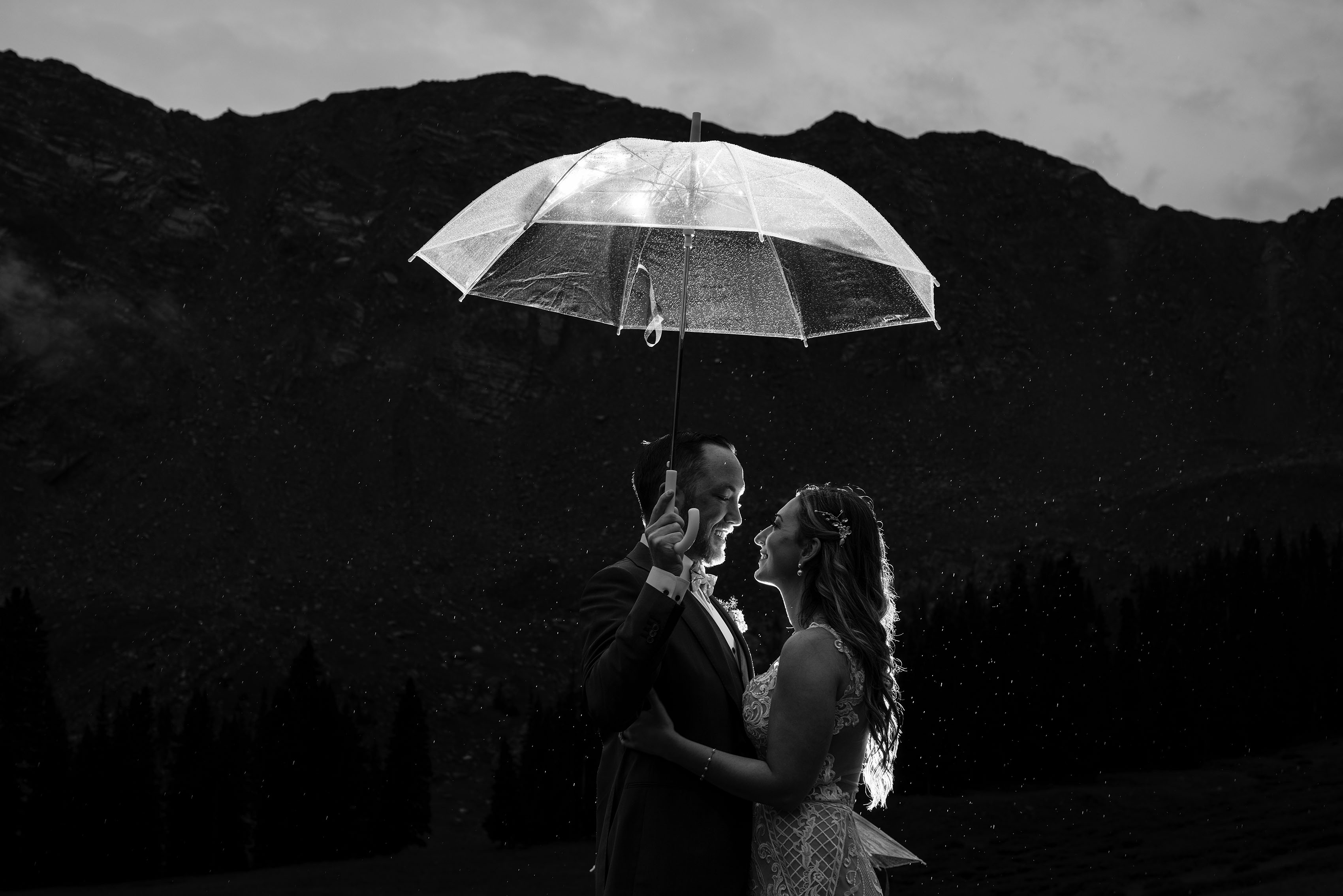 The newlyweds pose under and umbrella as it rains at A Basin