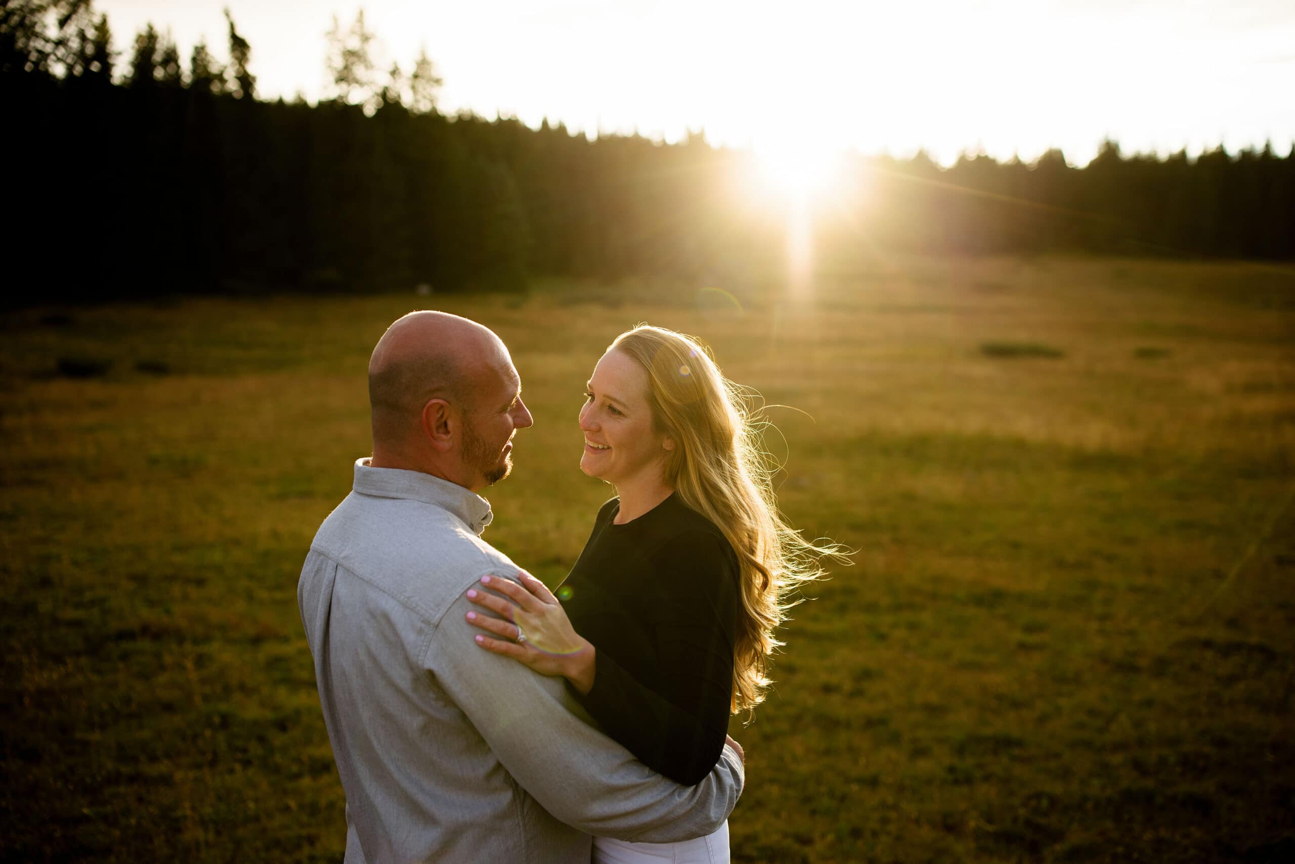 The sun sets behind David and Cassy as they embrace during their engagement at Shrine Pass