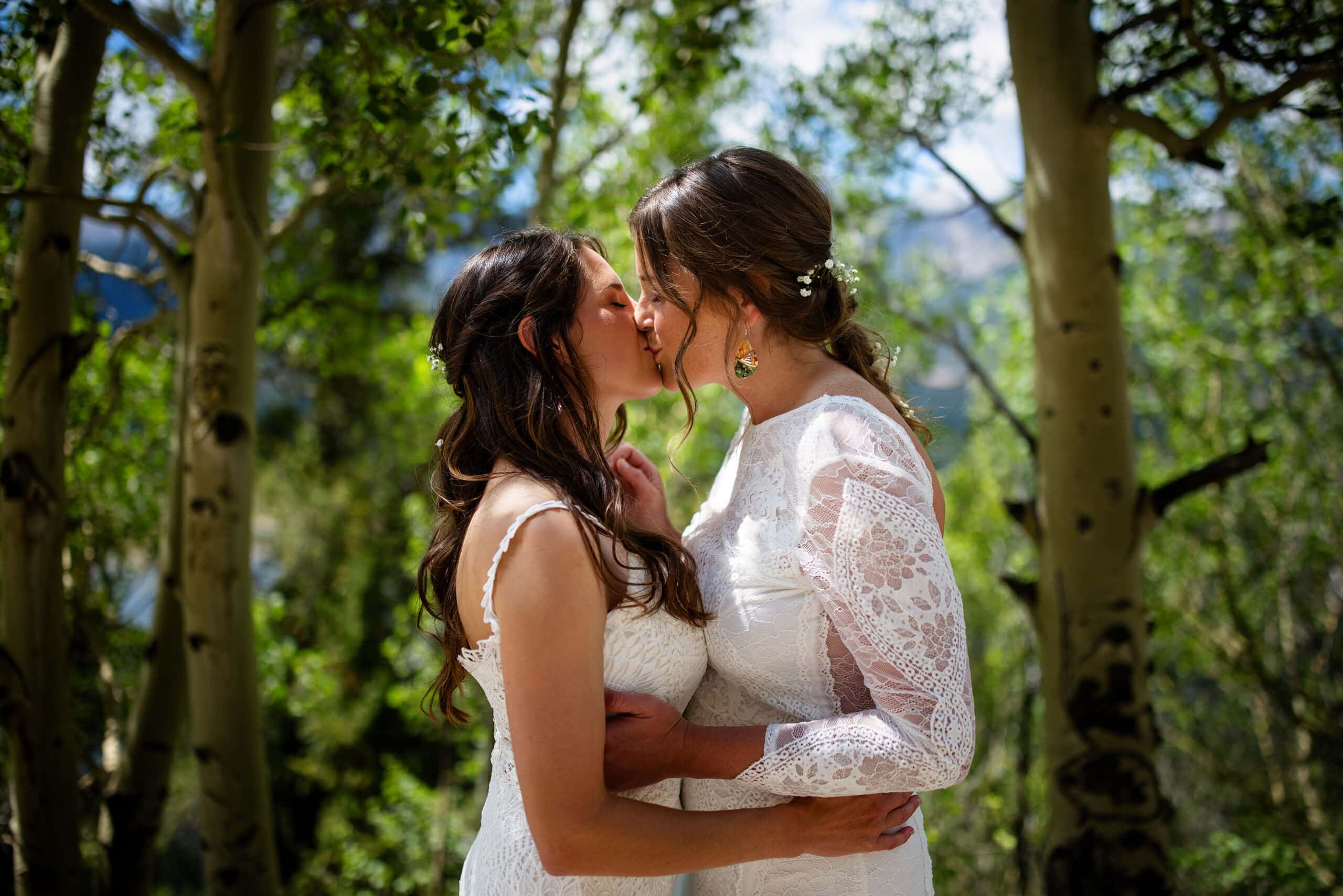 Anna and Cait share a kiss near an aspen grove in Breckenridge