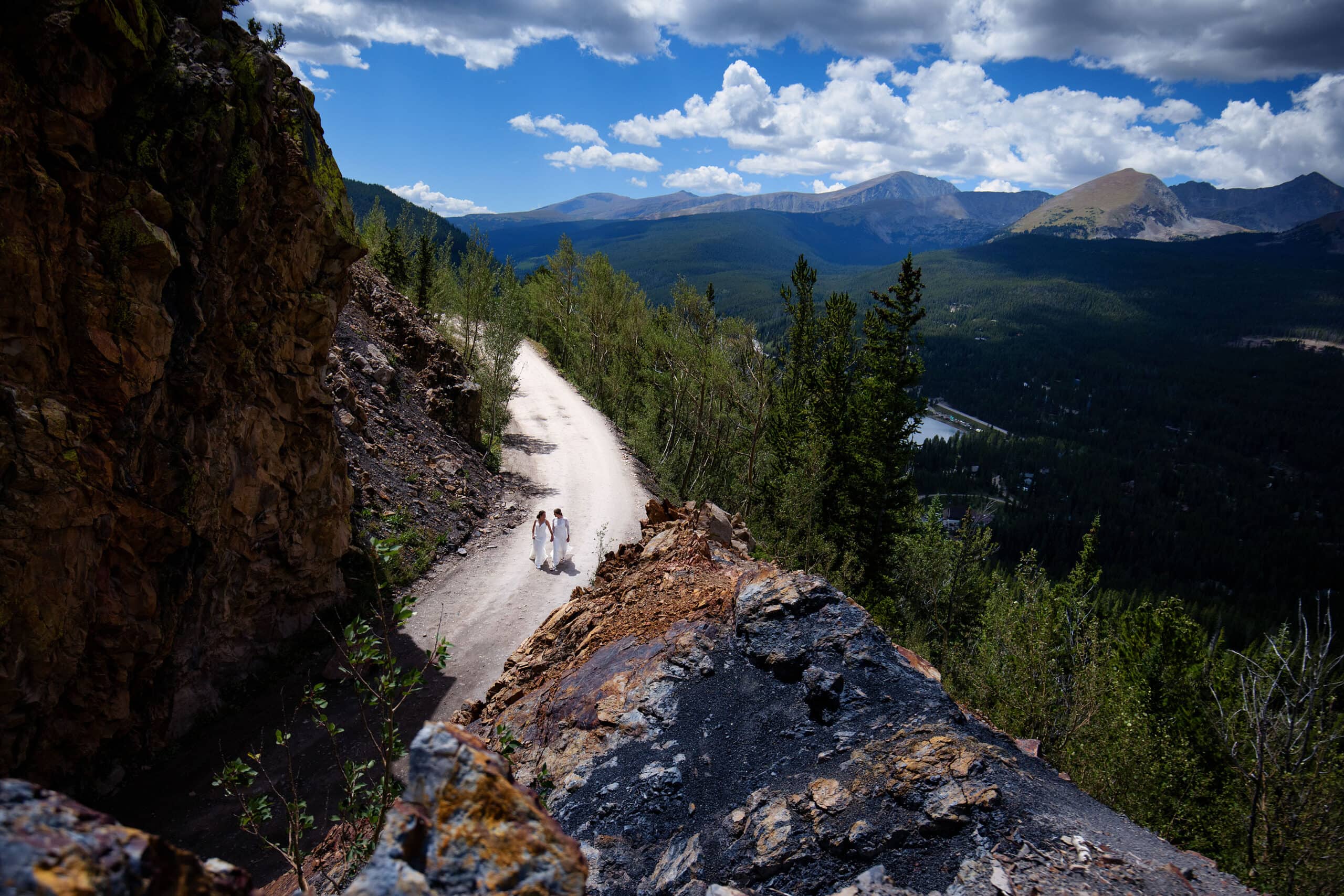 Two brides walk on Boreas Pass Road during their wedding day in Breckenridge