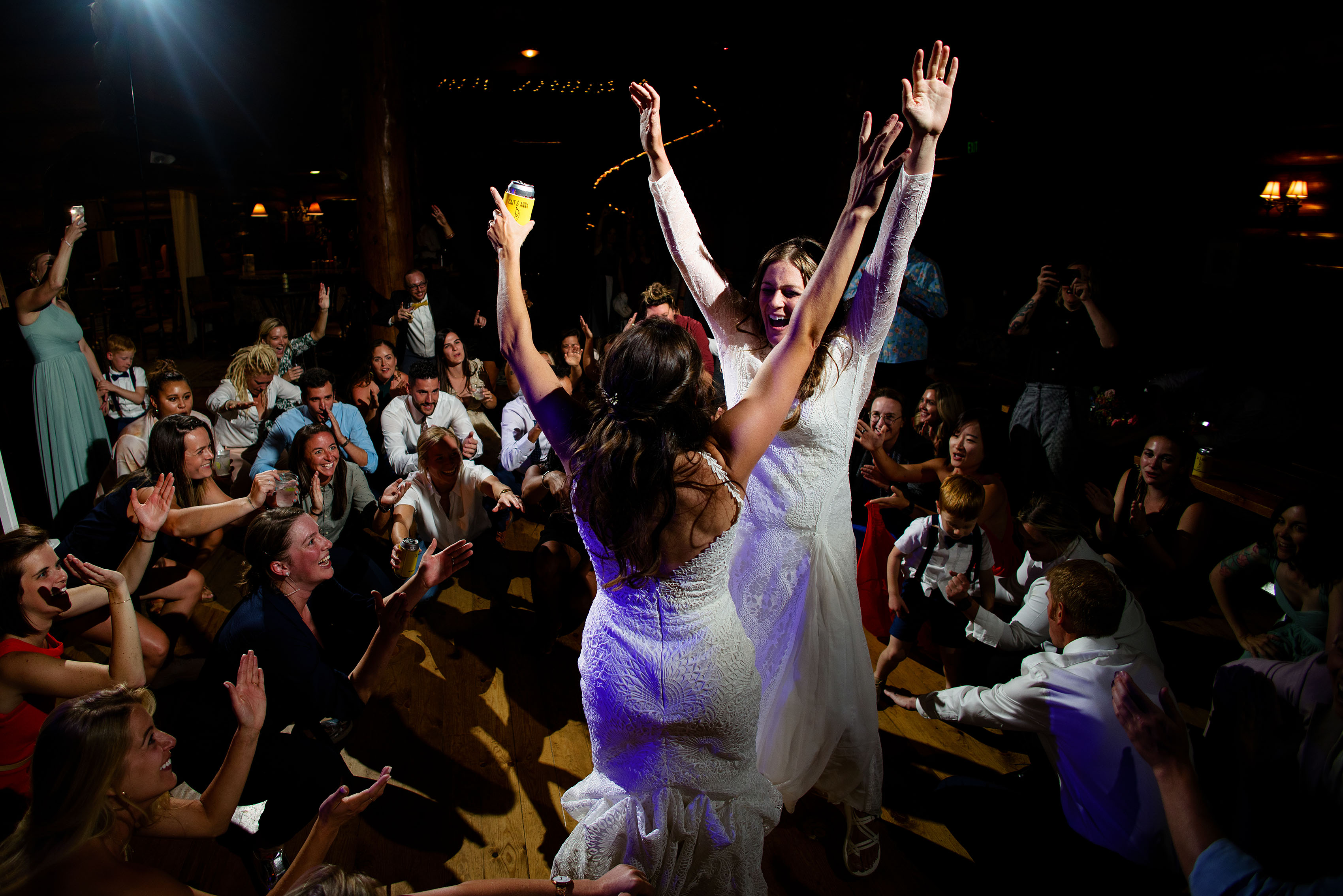 The brides cheer as guests dance together during a wedding reception at Breckenridge Nordic Center