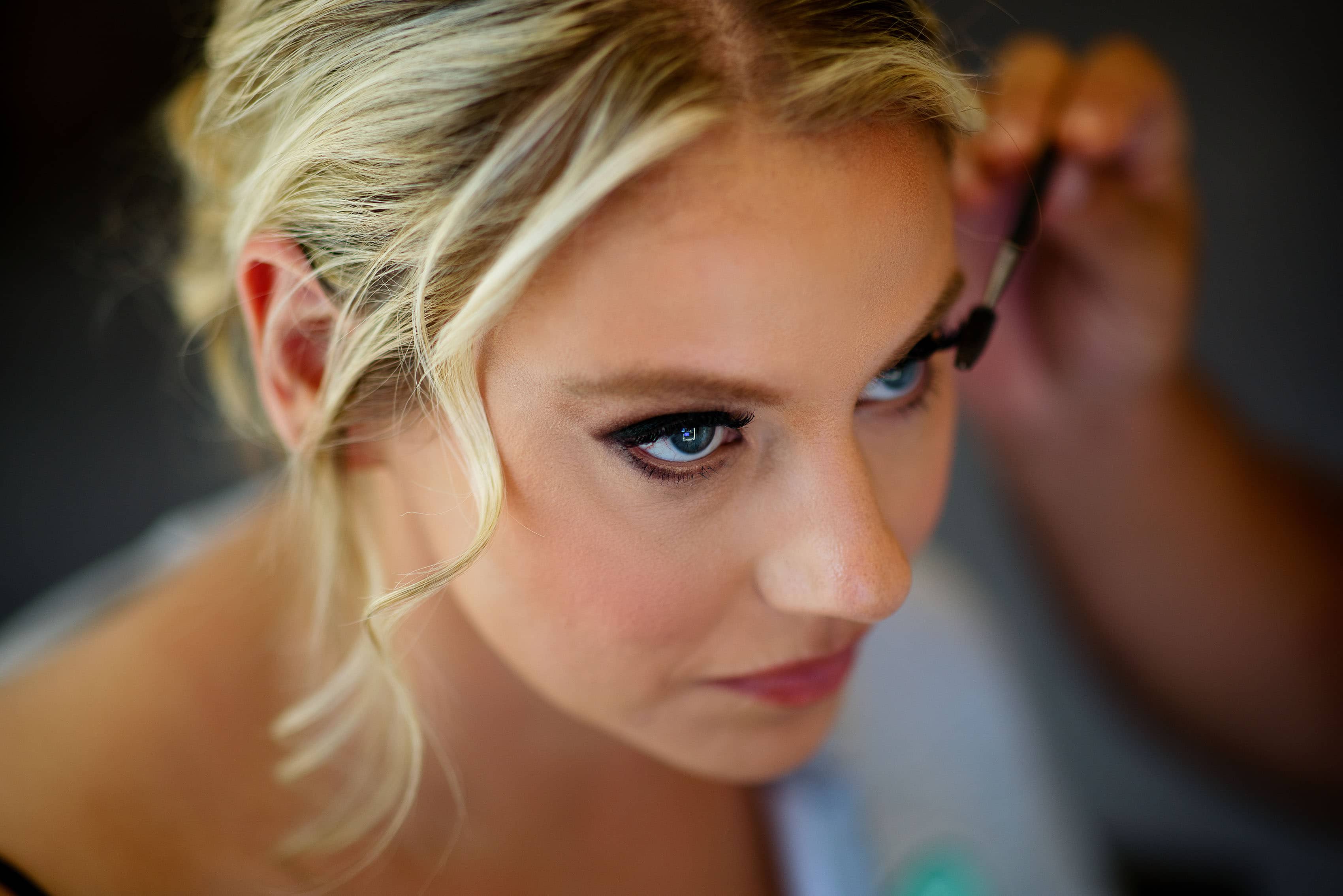 The bride gets mascara applied while getting ready