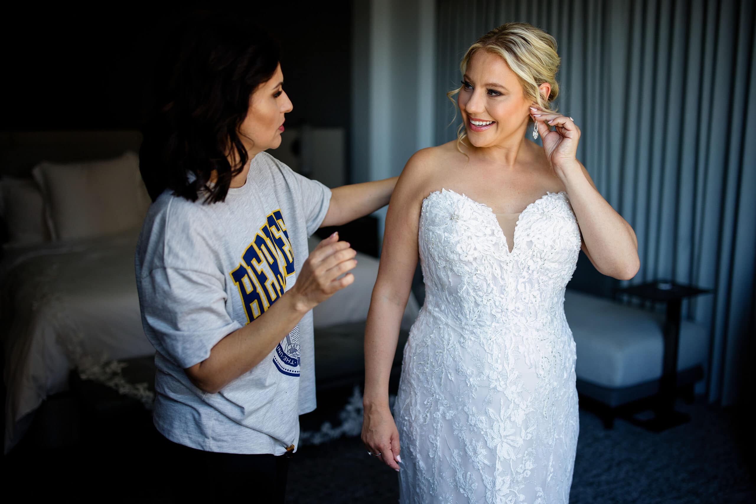 The bride puts on an earring as a family member looks on
