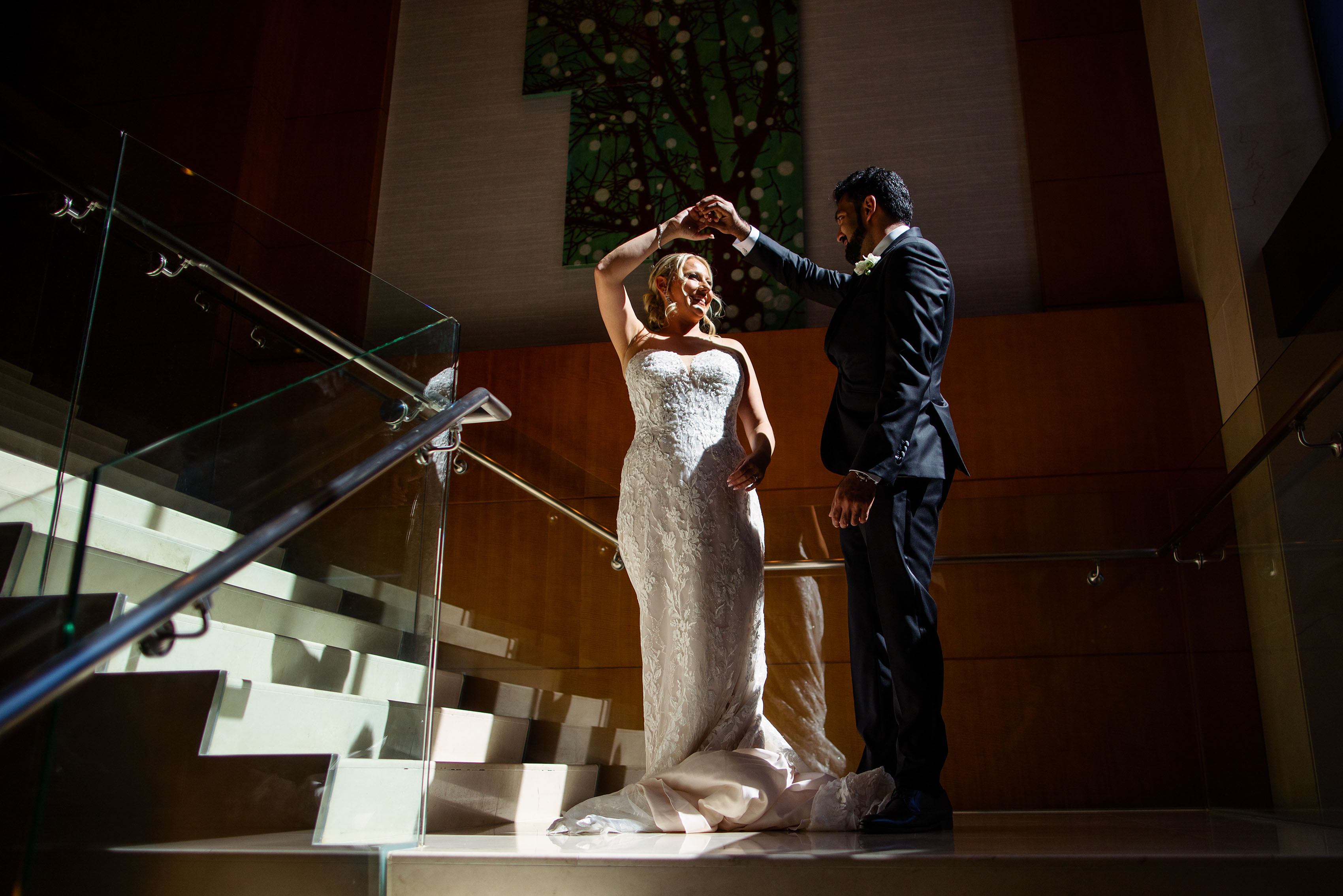The groom spins the bride on the staircase at Four Seasons Hotel Denver