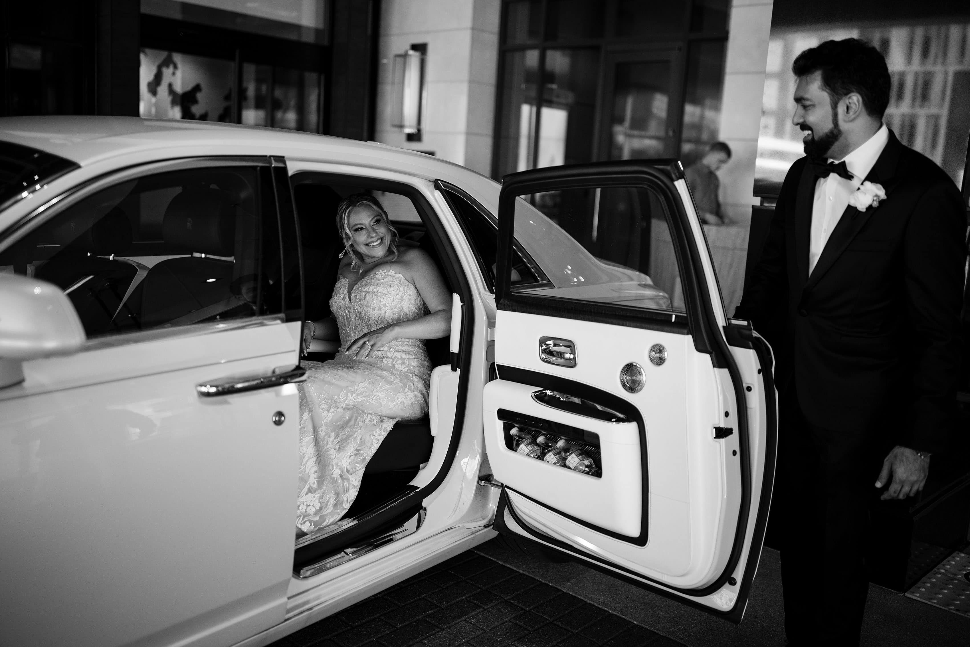 The groom helps the bride into a Rolls Royce