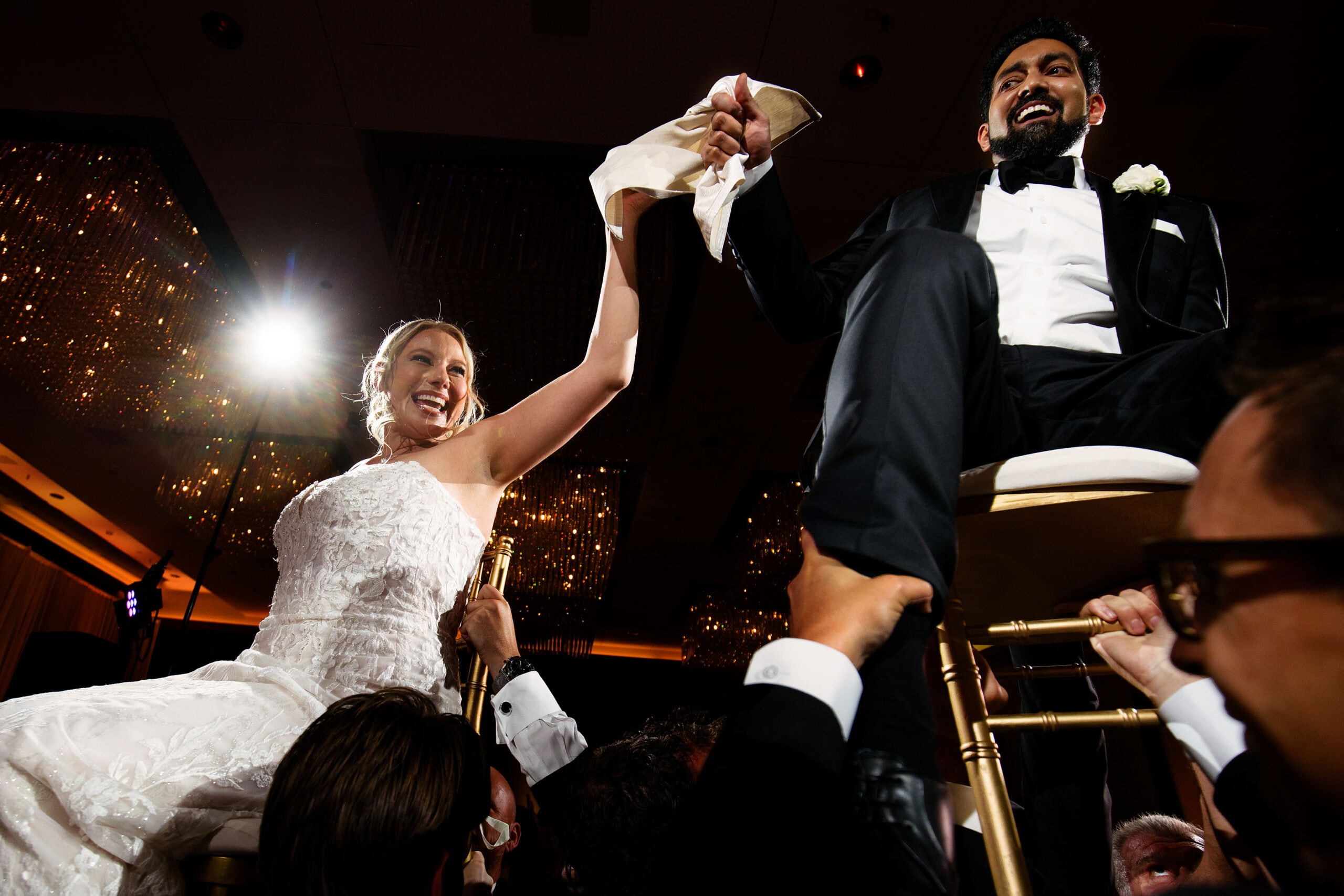 Jessica and Sambit are lifted in chairs on the dance floor during the hora at Four Seasons Hotel Denver