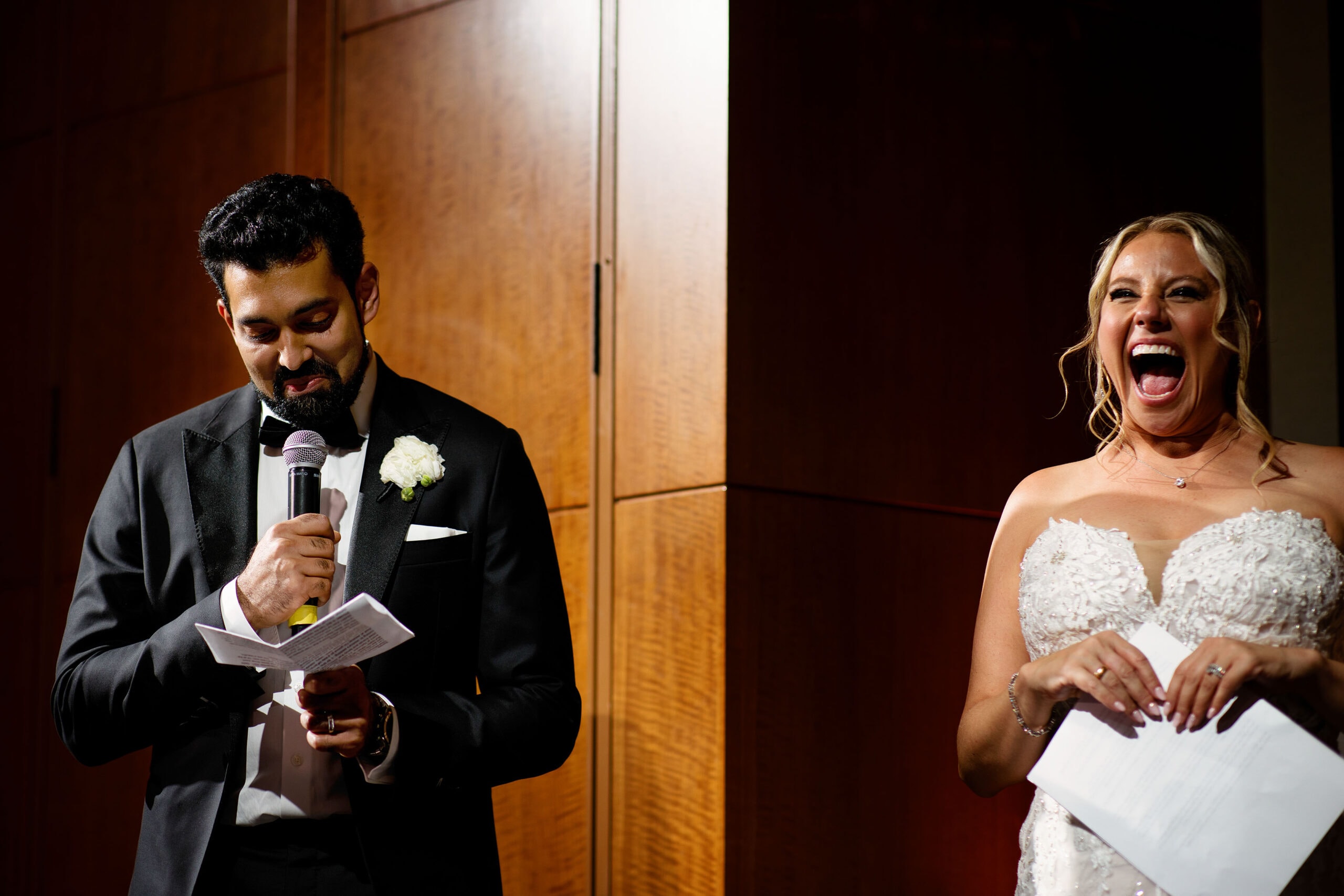 The bride laughs as the groom gives a toast during the wedding
