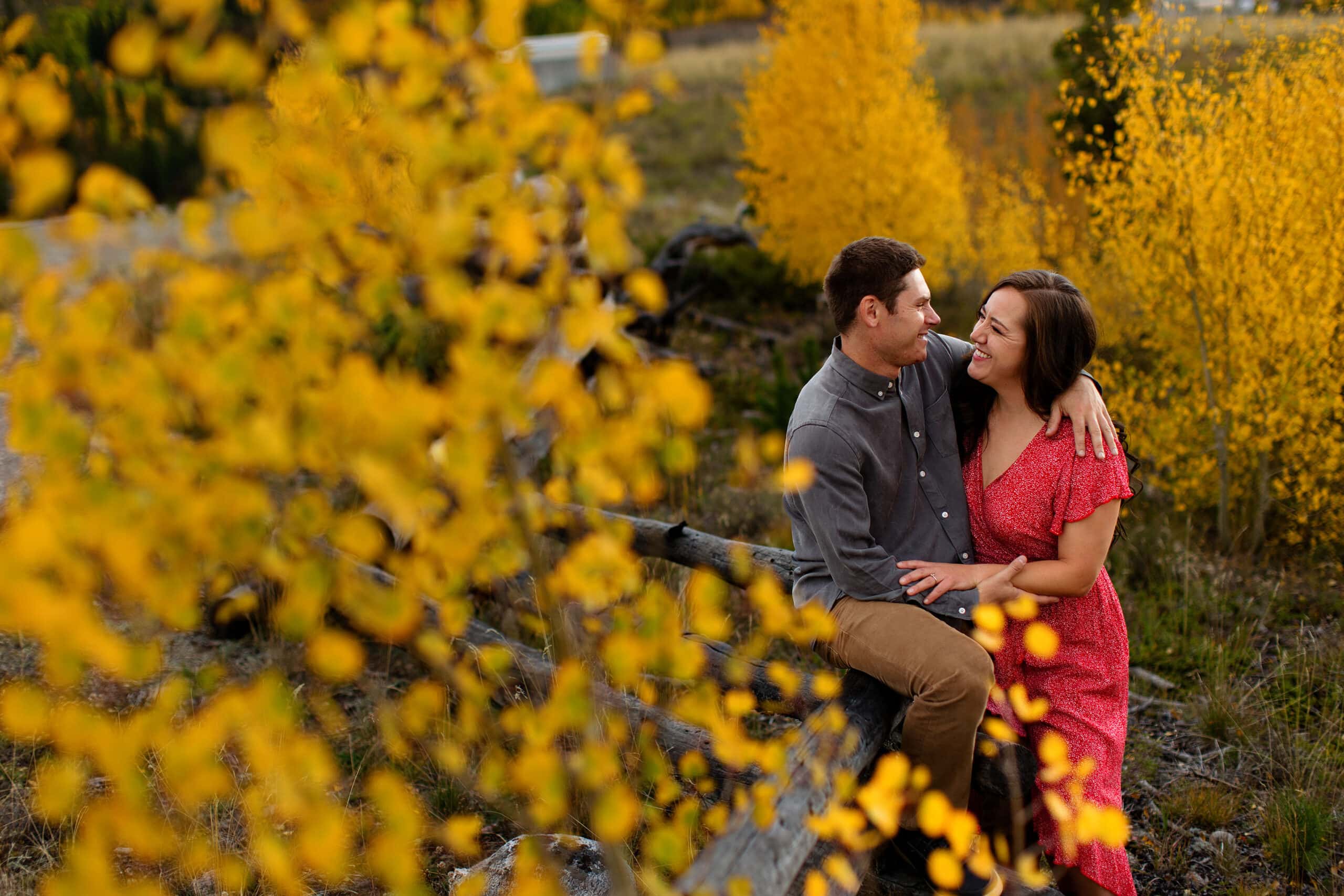 Gabe sits on a fence as Danielle smiles at him in Frisco, Colorado