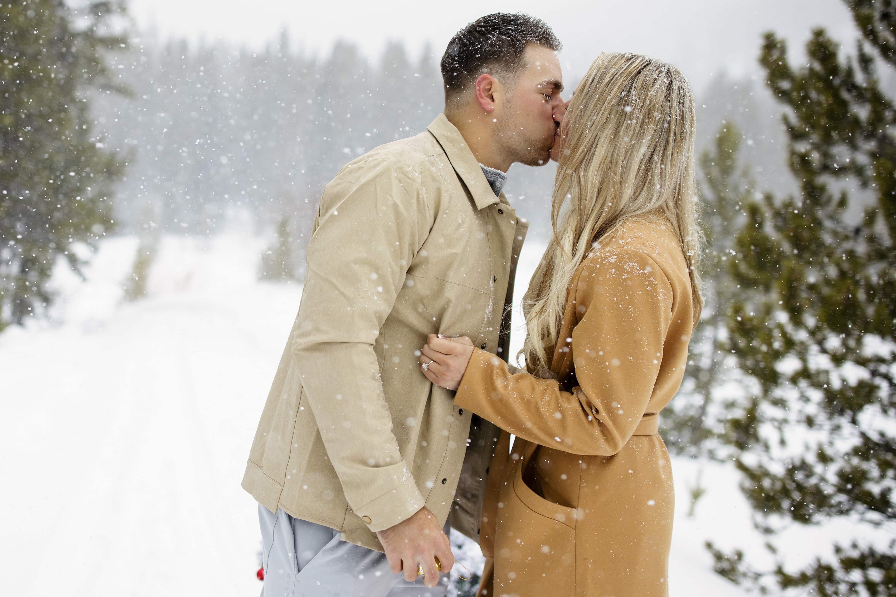 A couple kisses after getting engaged in the snow in Breckenridge