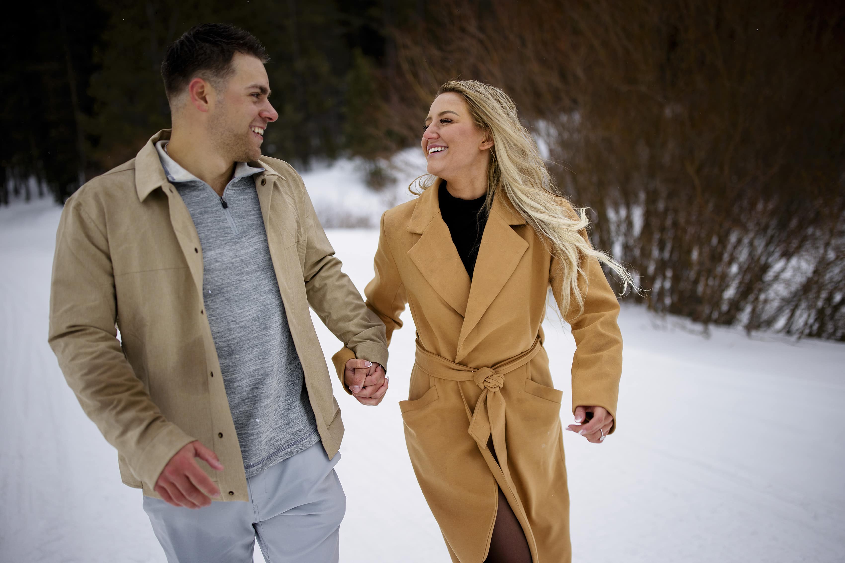 A newly engaged couple run in the snow in Breckenridge