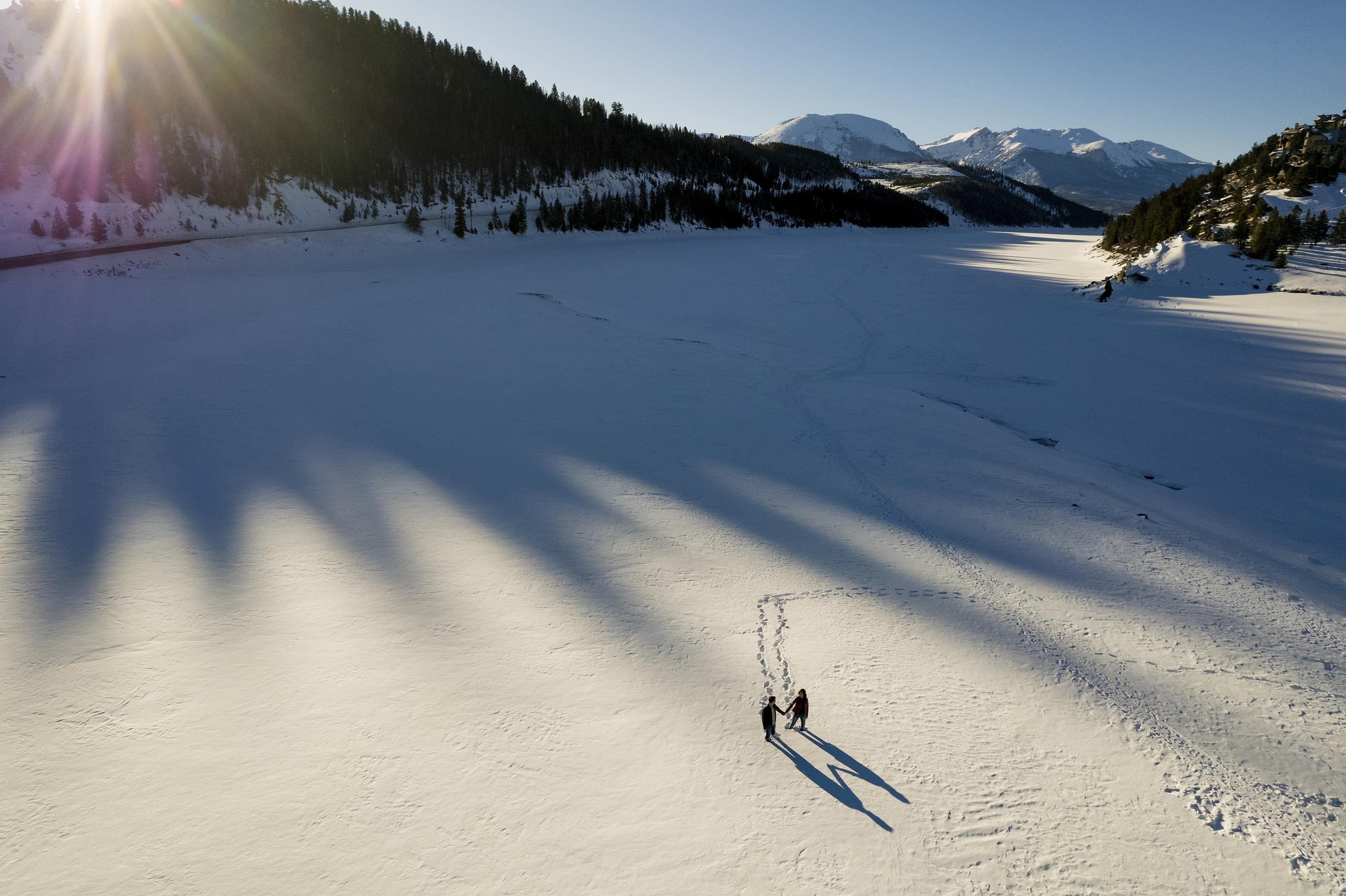 A couple walks in the snow at Dillon Reservoir during their winter engagement session