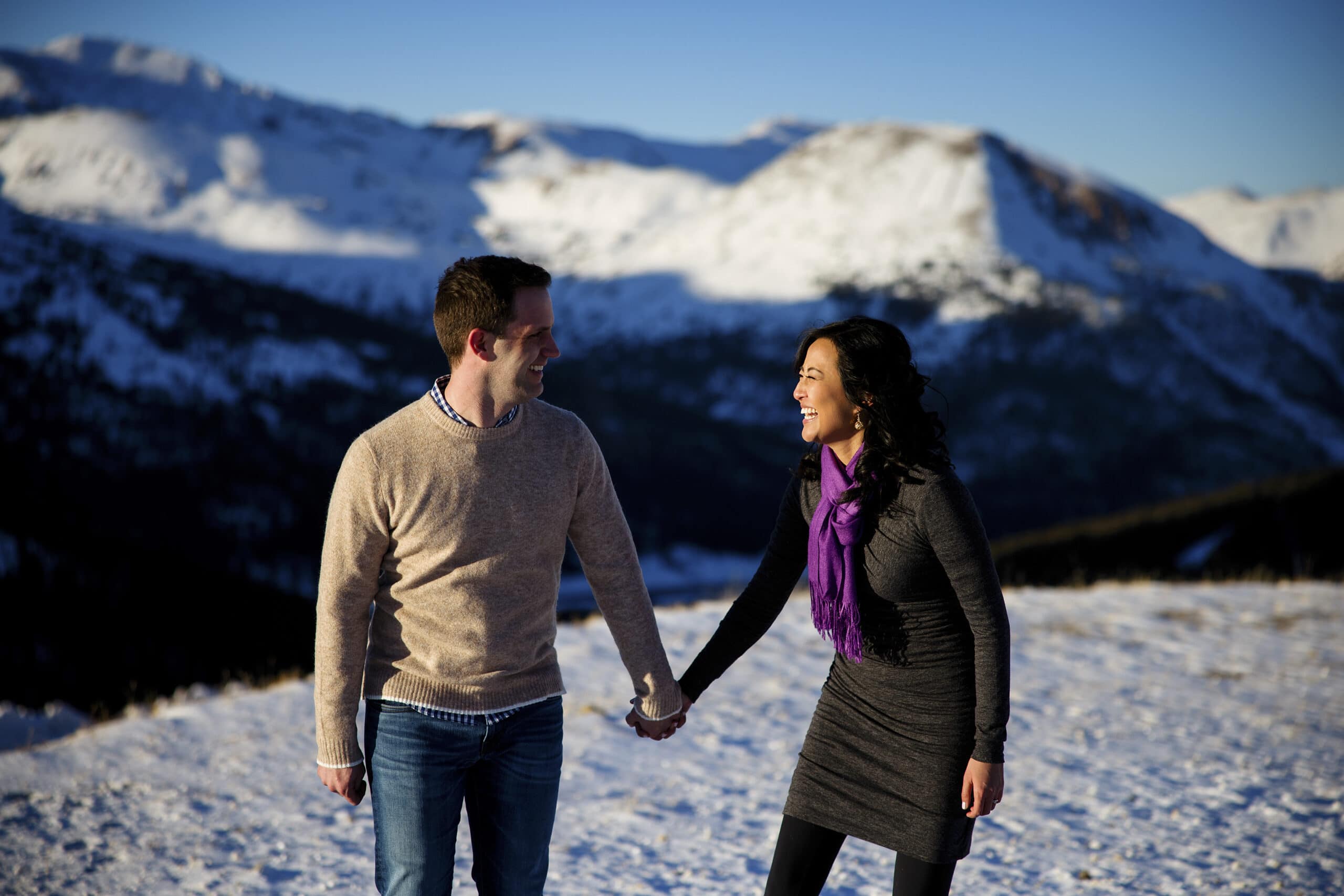 Brett and Nicole laugh together on top of Loveland Pass  during their winter engagement photos