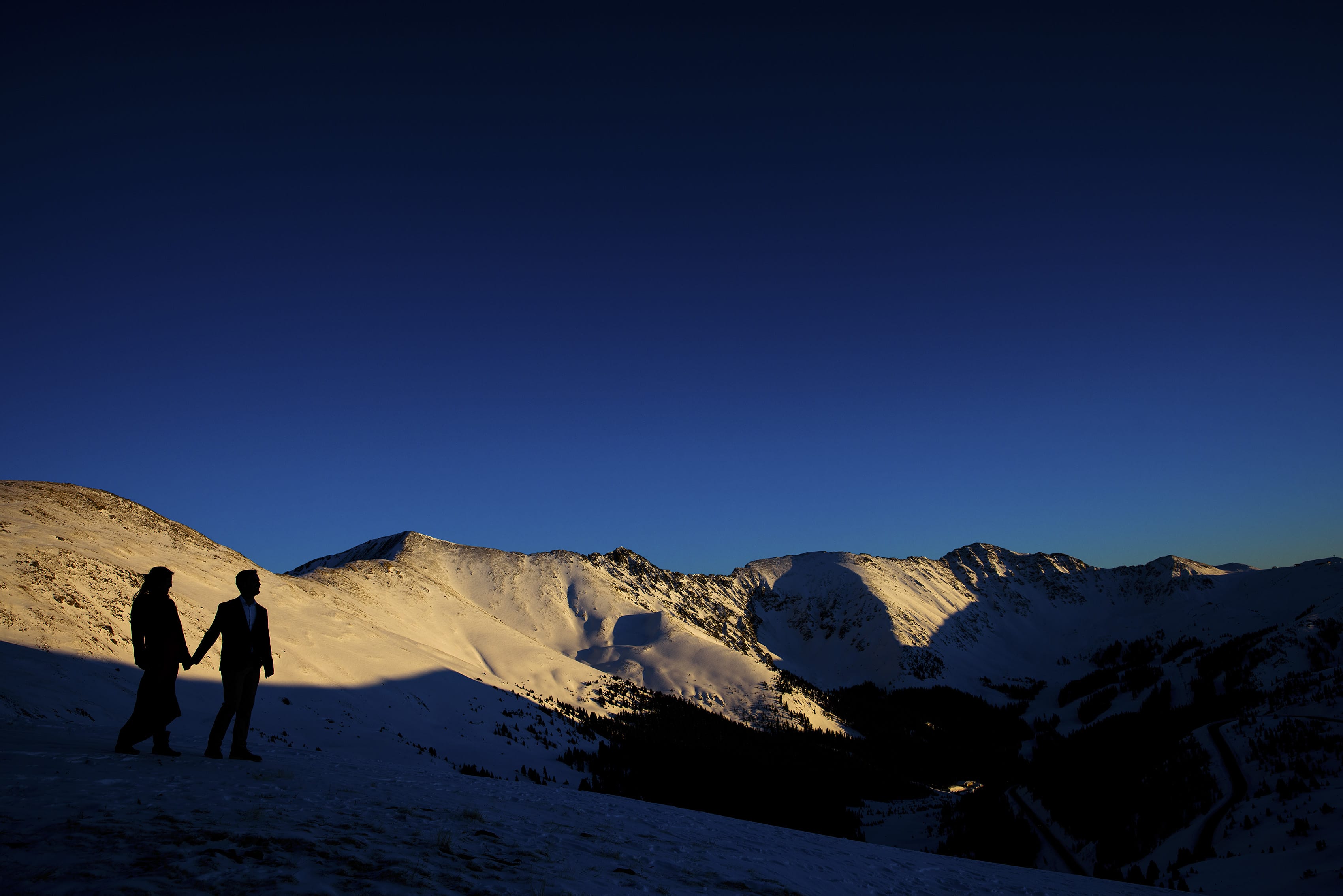 A couple is silhouetted against the mountains on Loveland Pass during their winter photo session