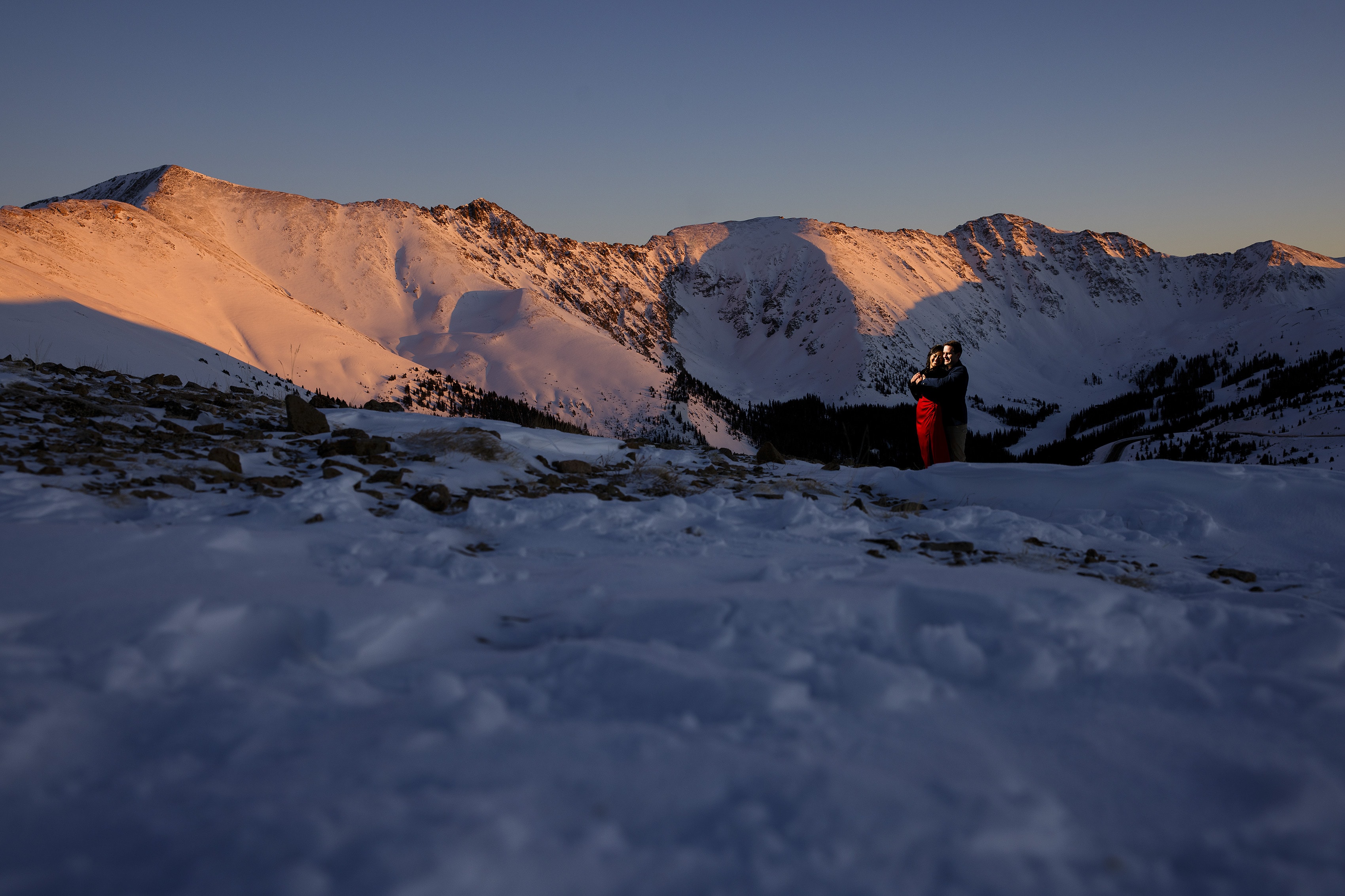 Nicole and Brett embrace as alpenglow illuminates the East Wall of Arapahoe Basin ski area as seen from Loveland Pass in Colorado