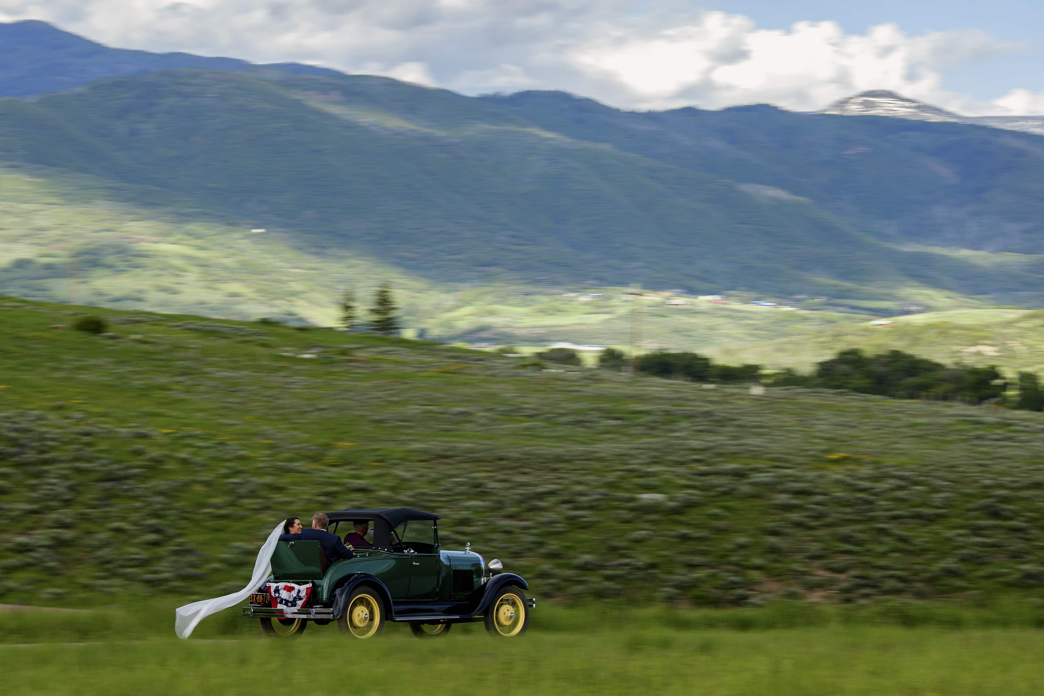 The newlyweds drive away in a Model A vintage car in the hills of Steamboat Springs