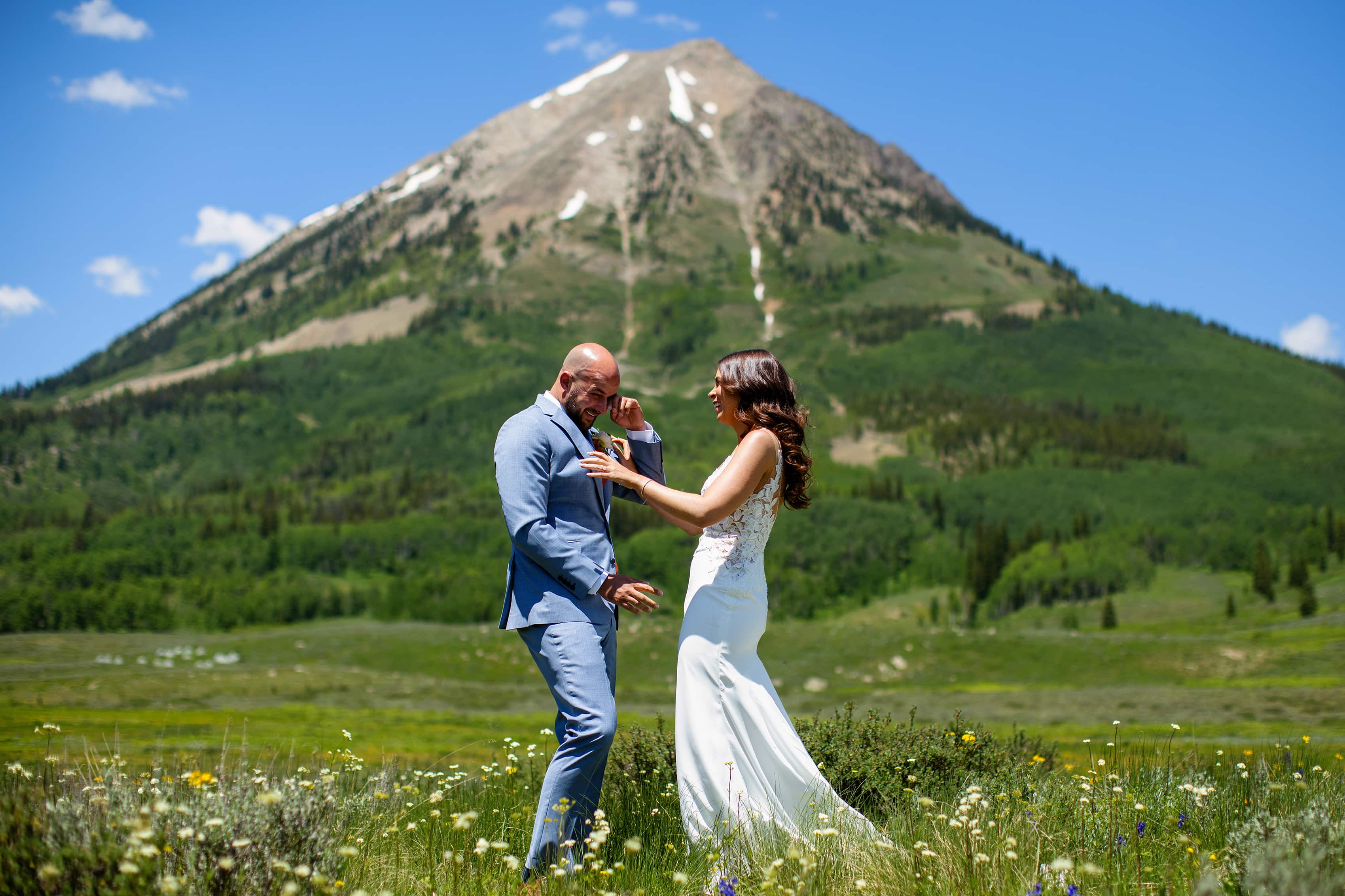 The groom wipes away a tear during their first look near Mount Gothic in Crested Butte
