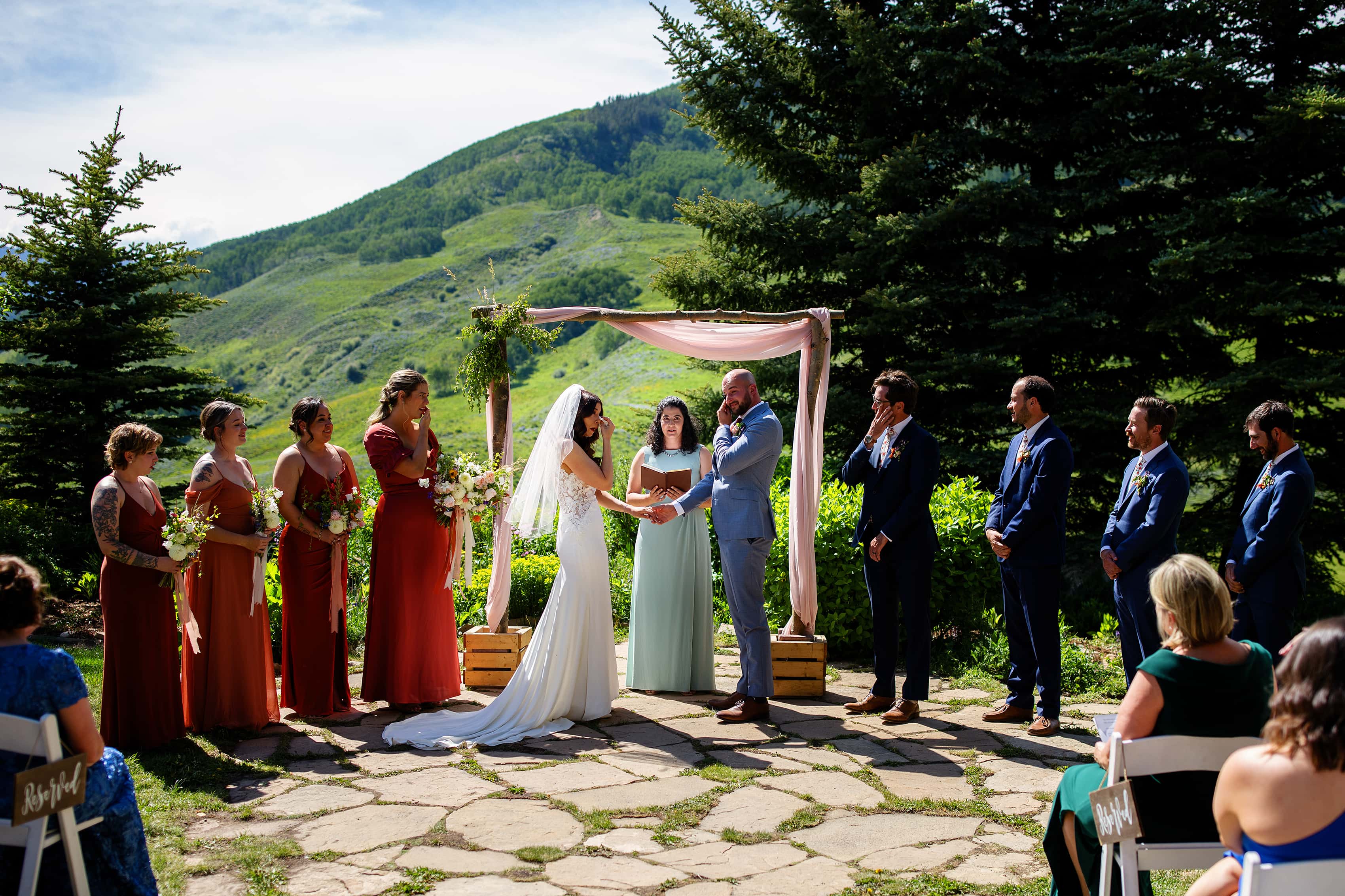 The bride and groom wipe away tears during their ceremony at Mountain Wedding Garden