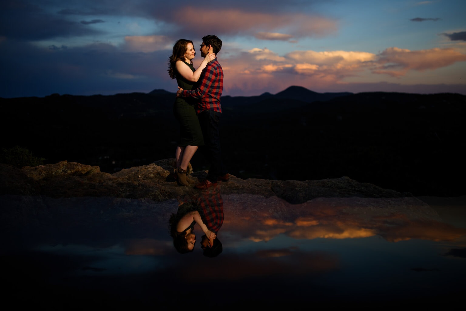 Felicia and Dan are reflected in a pond during sunset atop Brothers Lookout in Alderfer/Three Sisters Park in Evergreen