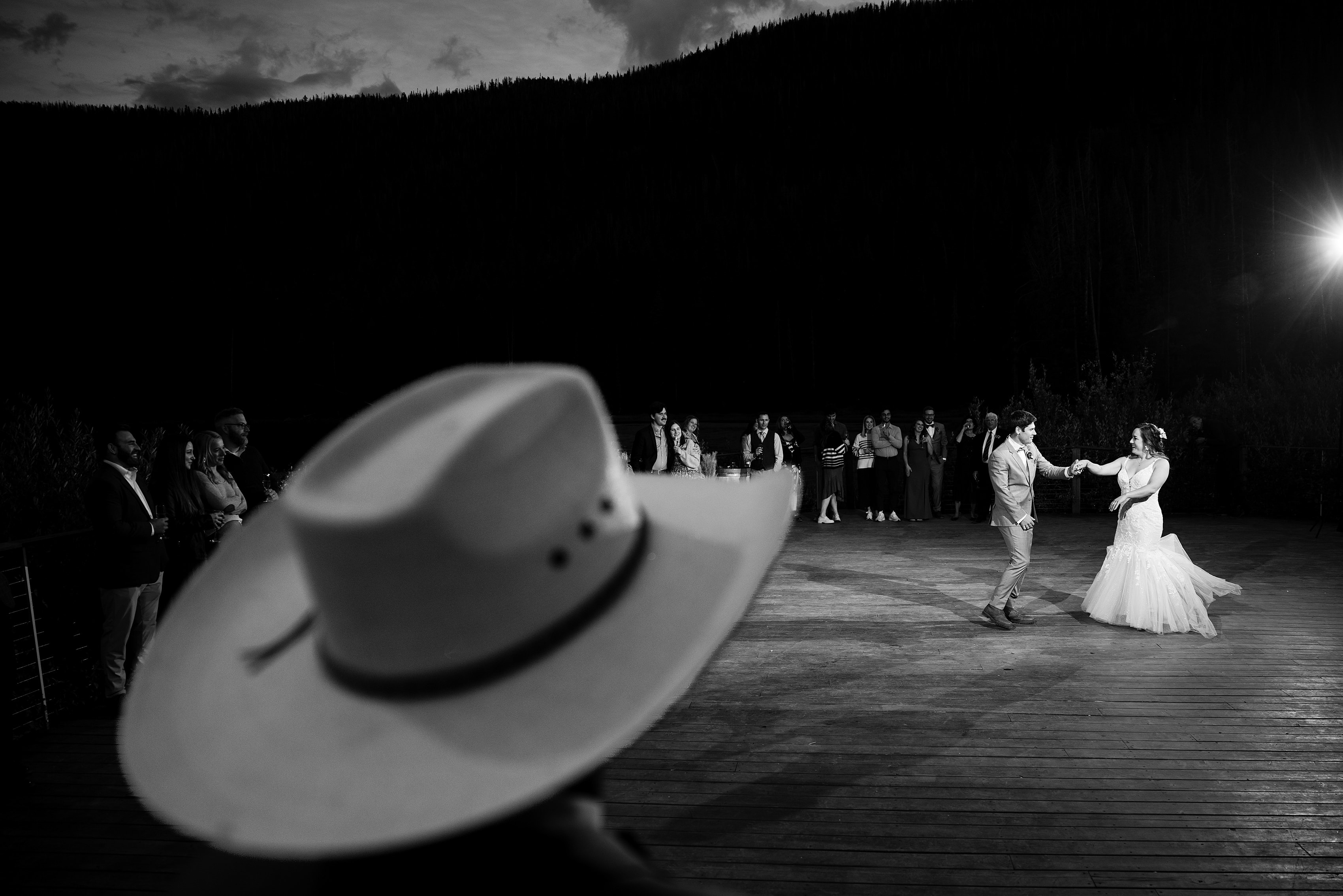 A guest wearing a cowboy hat looks on during Danielle and Gabe’s first dance at Piney River Ranch