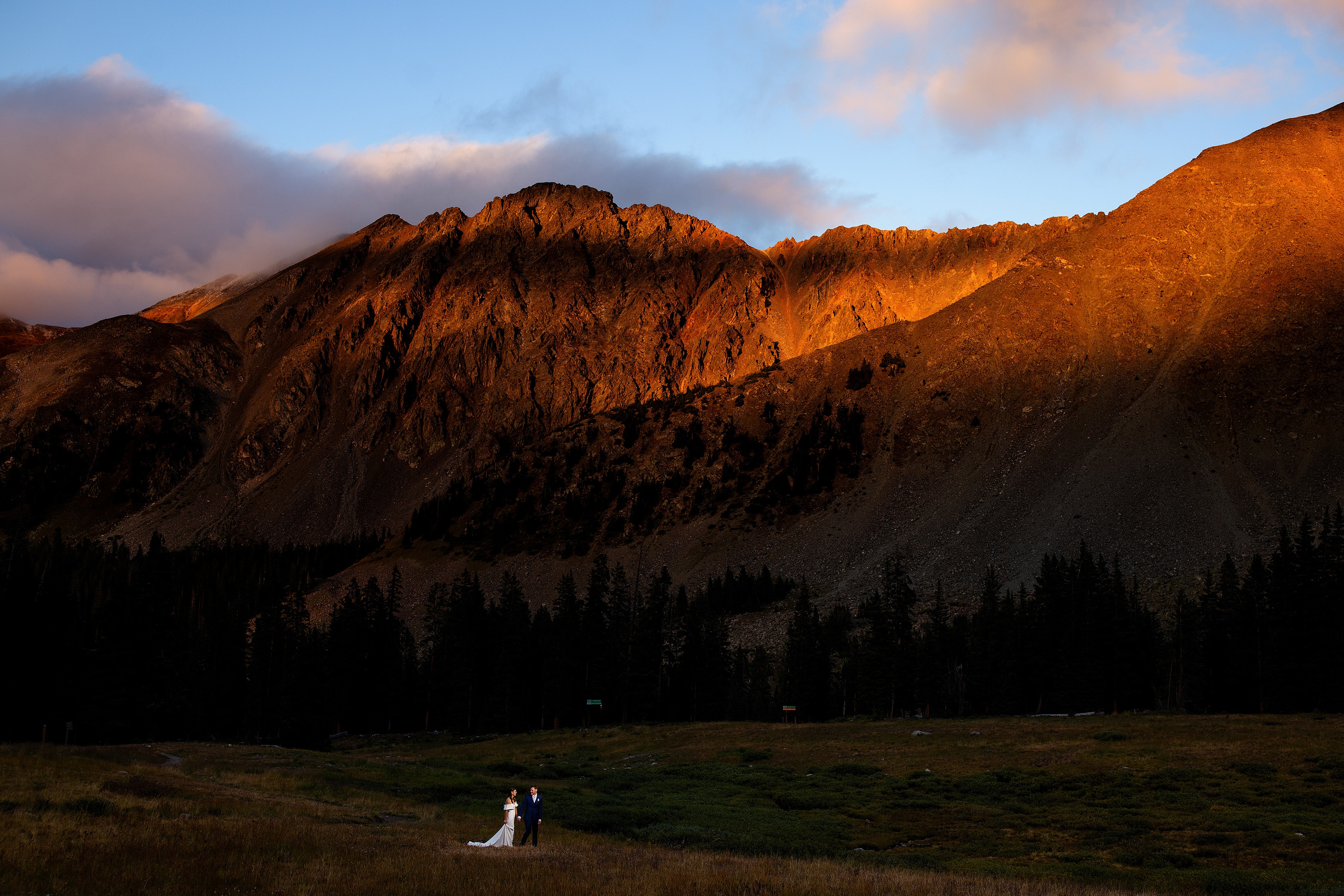 Heather and Stephen pose together as alpenglow illuminates the East Wall at Arapahoe Basin during their wedding day